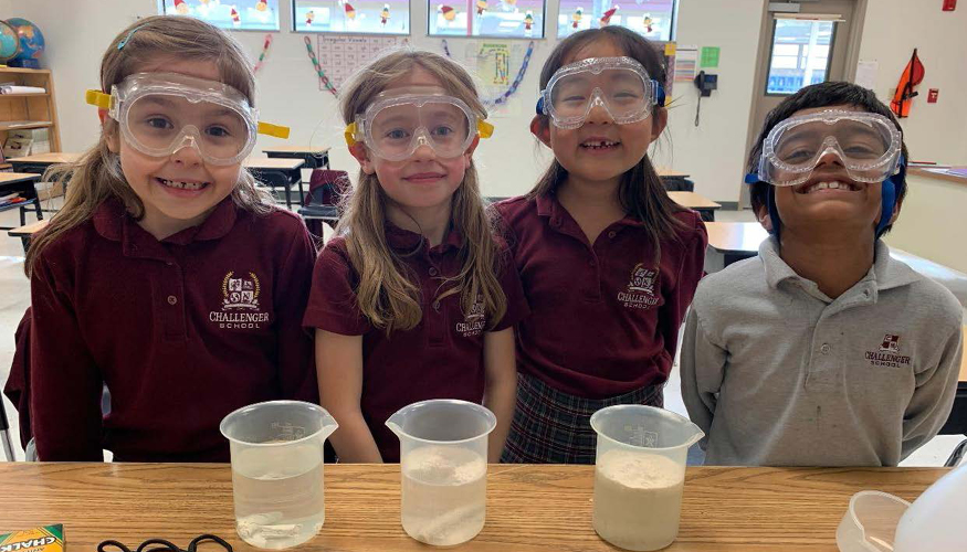 Four smiling Challenger students with their Science Fair project