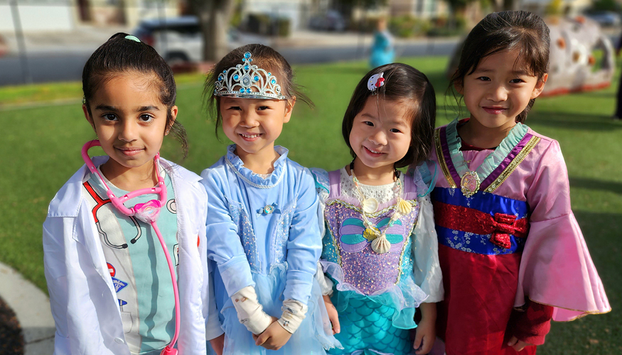 Four happy students wearing Halloween costumes